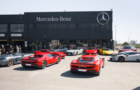 Colección de superdeportivos Ferrari, Lamborghini y Mercedes aparcados frente al concesionario Mercedes-Benz